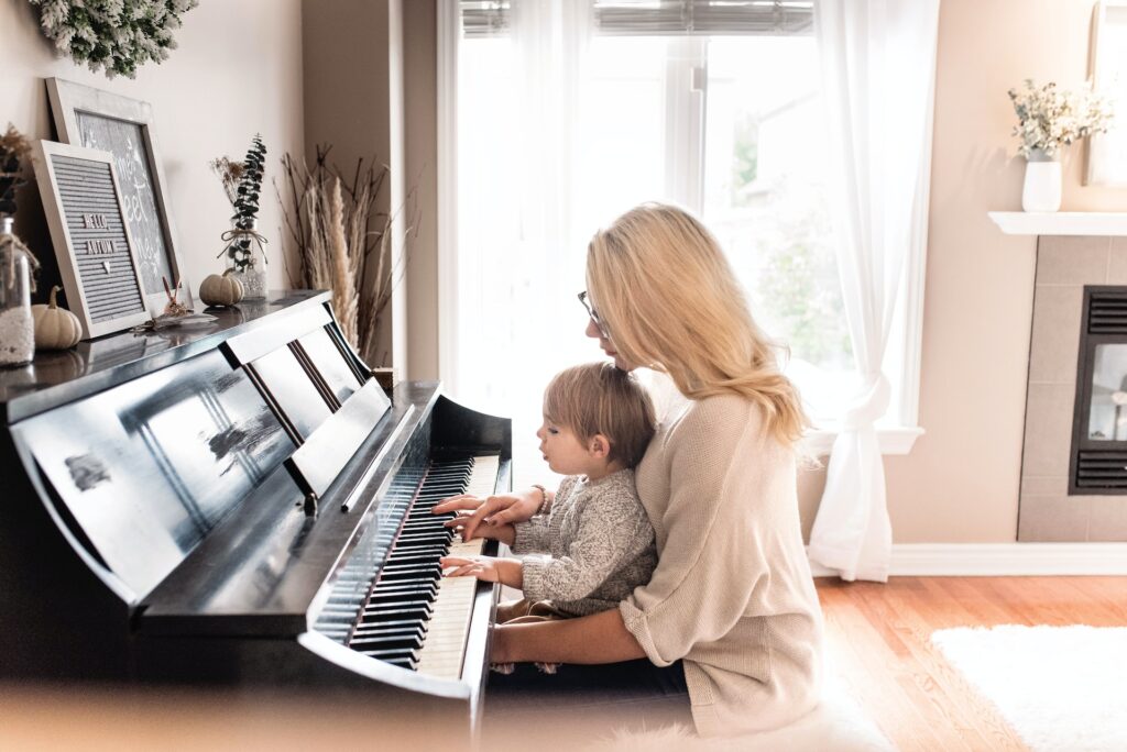 Mom is playing piano and singing with little toddler, teaching kids music, early childhood musical education